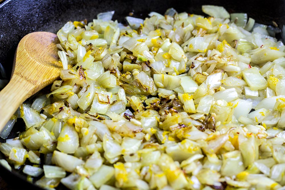 Adding Garlic & Orange Zest to Orzo Recipe in Cast Iron Skillet