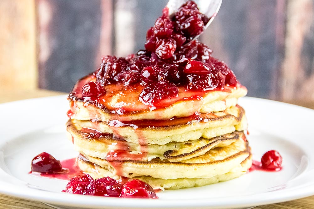 Adding Cranberry Syrup to Stack of Pancakes