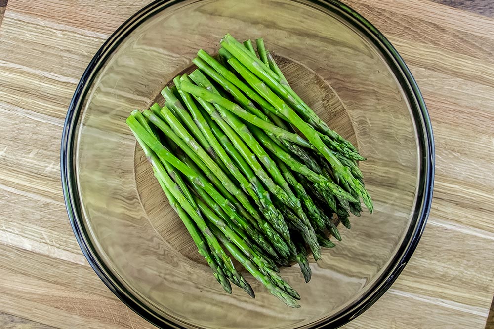 Raw Asparagus Coated With Olive Oil in Bowl